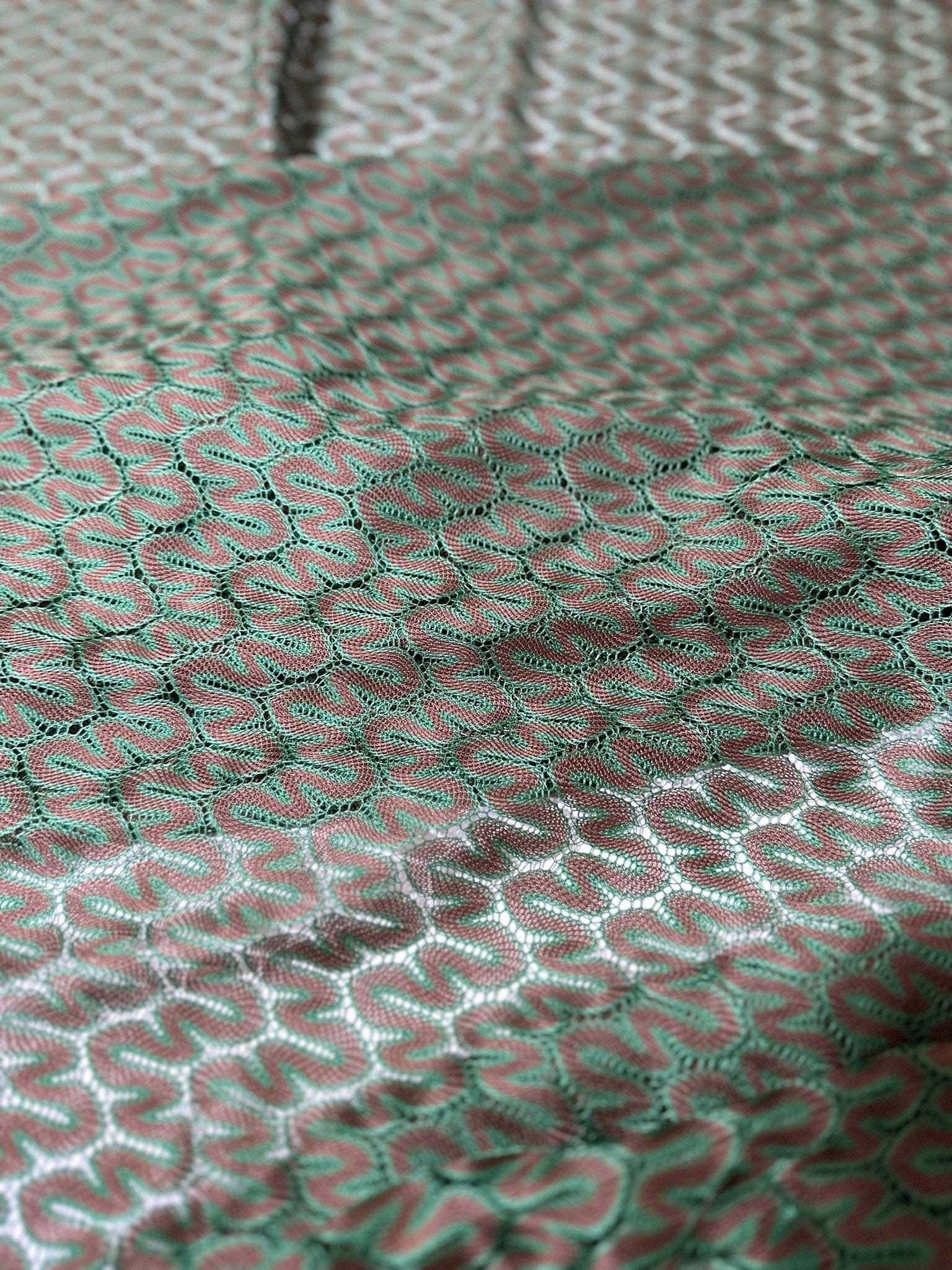 Close-up of green and brown zigzag knit jersey mesh fabric with textured pattern and soft drape