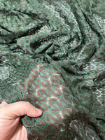 Green and Brown Zigzag Knit Jersey Mesh Fabric with textured zigzag pattern held in hand