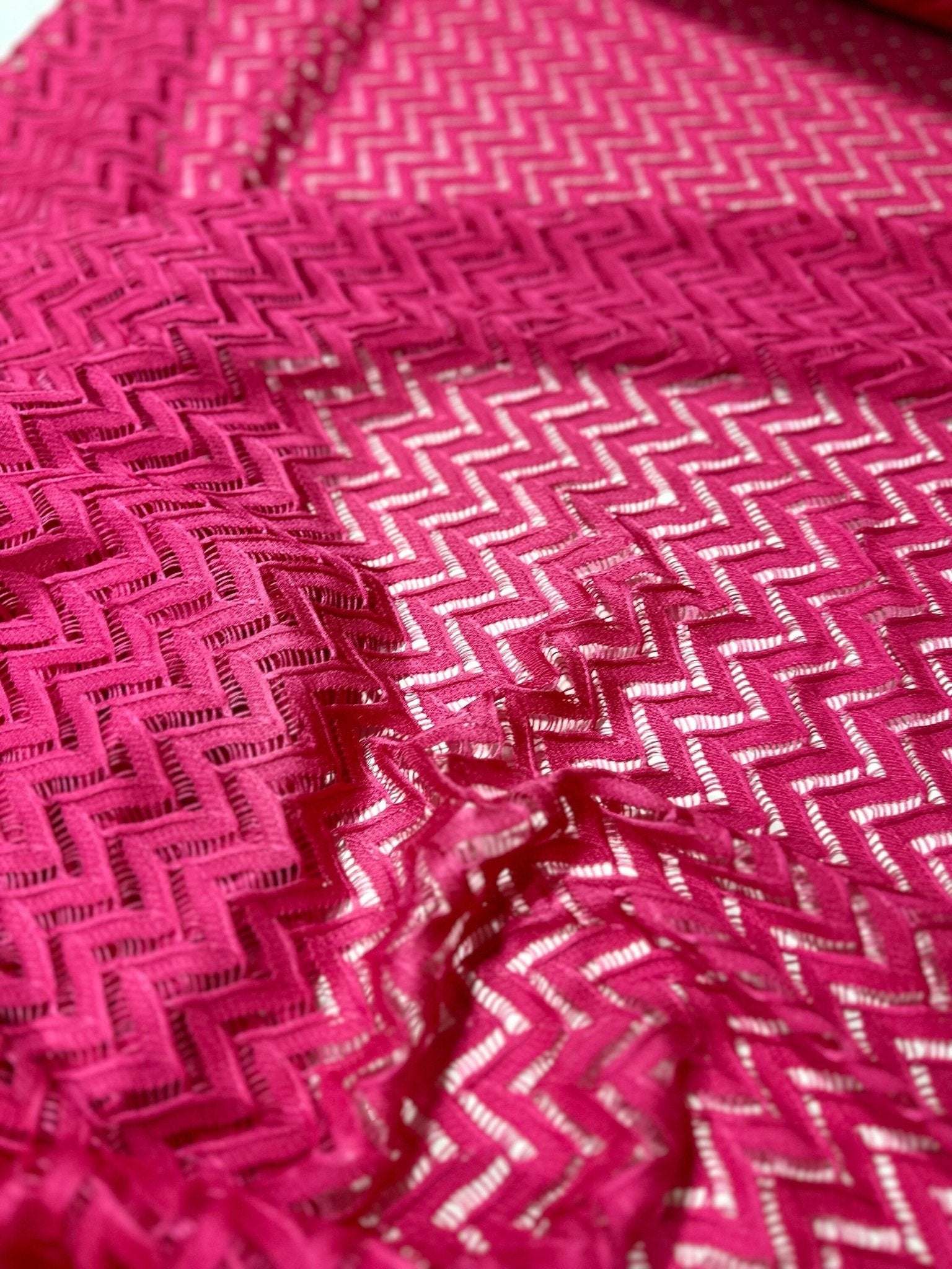 Pink zigzag knit jersey mesh fabric with intricate pattern for sewing and crafting projects