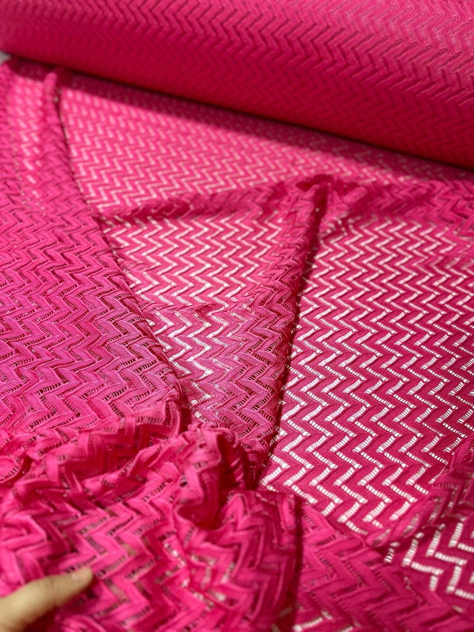 Pink zigzag knit jersey fabric with mesh texture, ideal for sewing and crafting projects