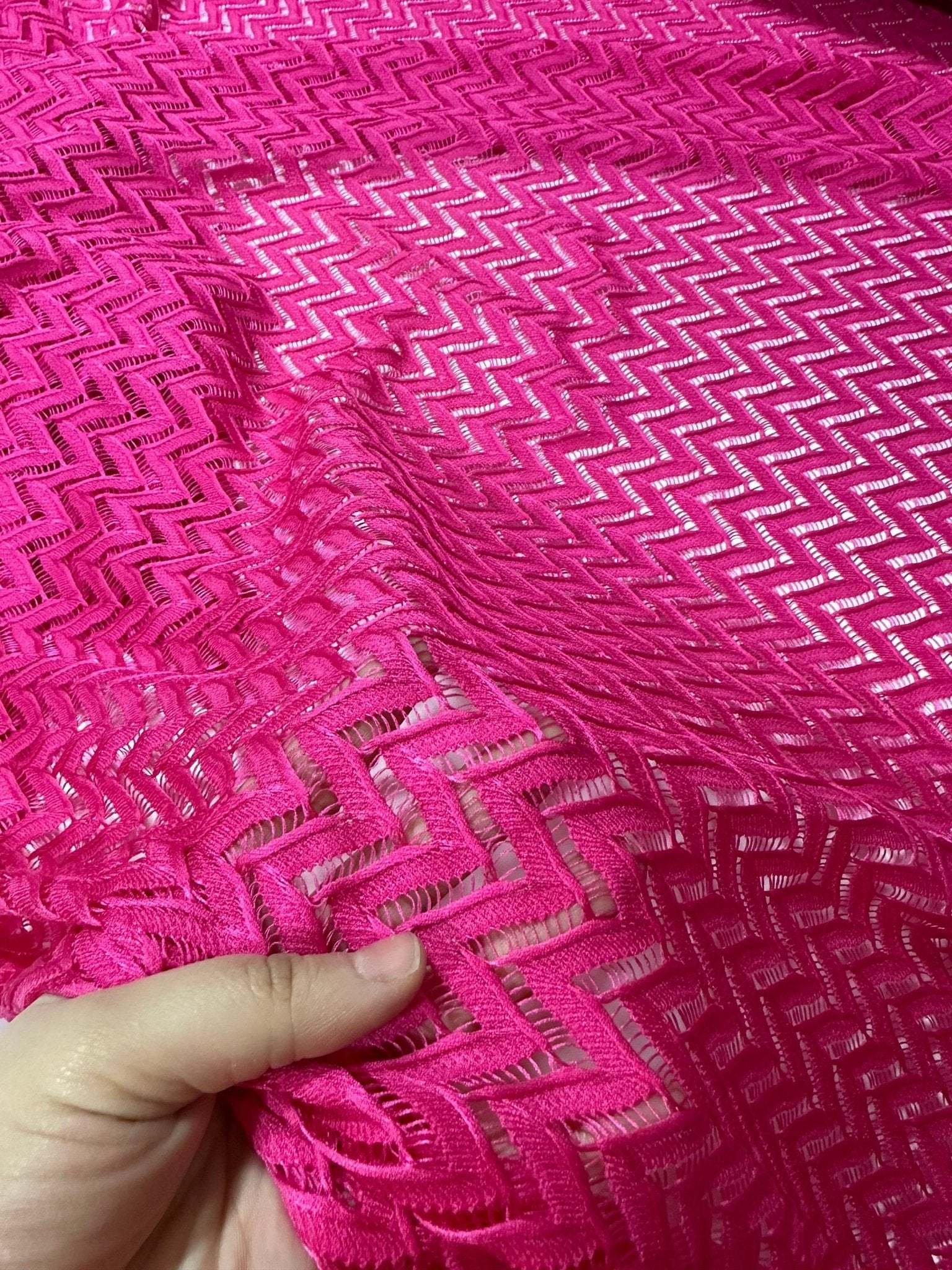 Pink zigzag knit jersey mesh fabric held in hand for crafting and sewing projects