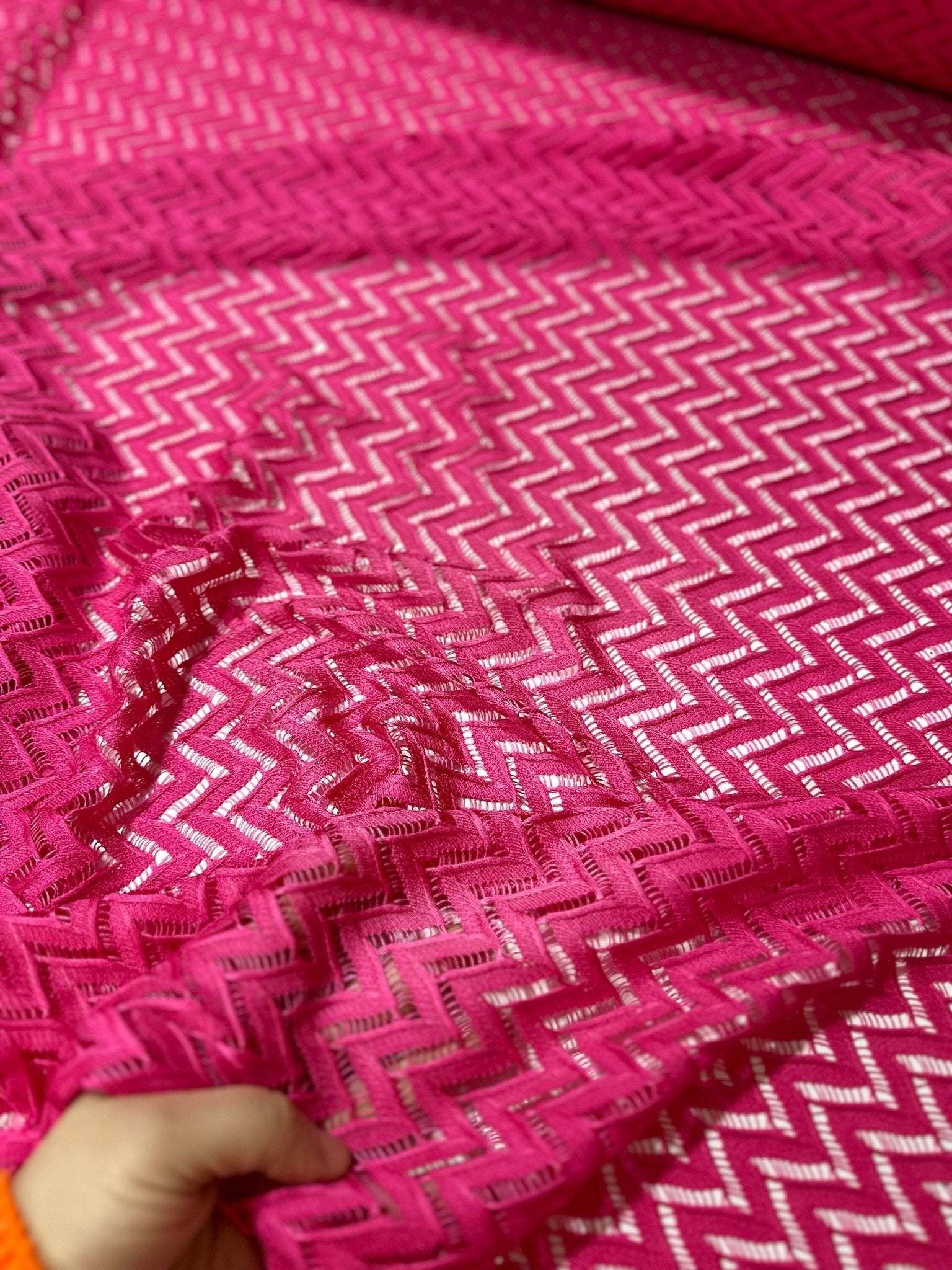 Pink mesh zigzag knit jersey fabric with chevron pattern for sewing and crafting projects