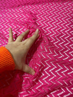 Hand touching vibrant pink zigzag knit jersey fabric with mesh texture for sewing and crafting projects