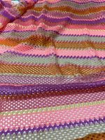 Pink striped knit jersey fabric with vibrant mesh texture and multicolor horizontal stripes