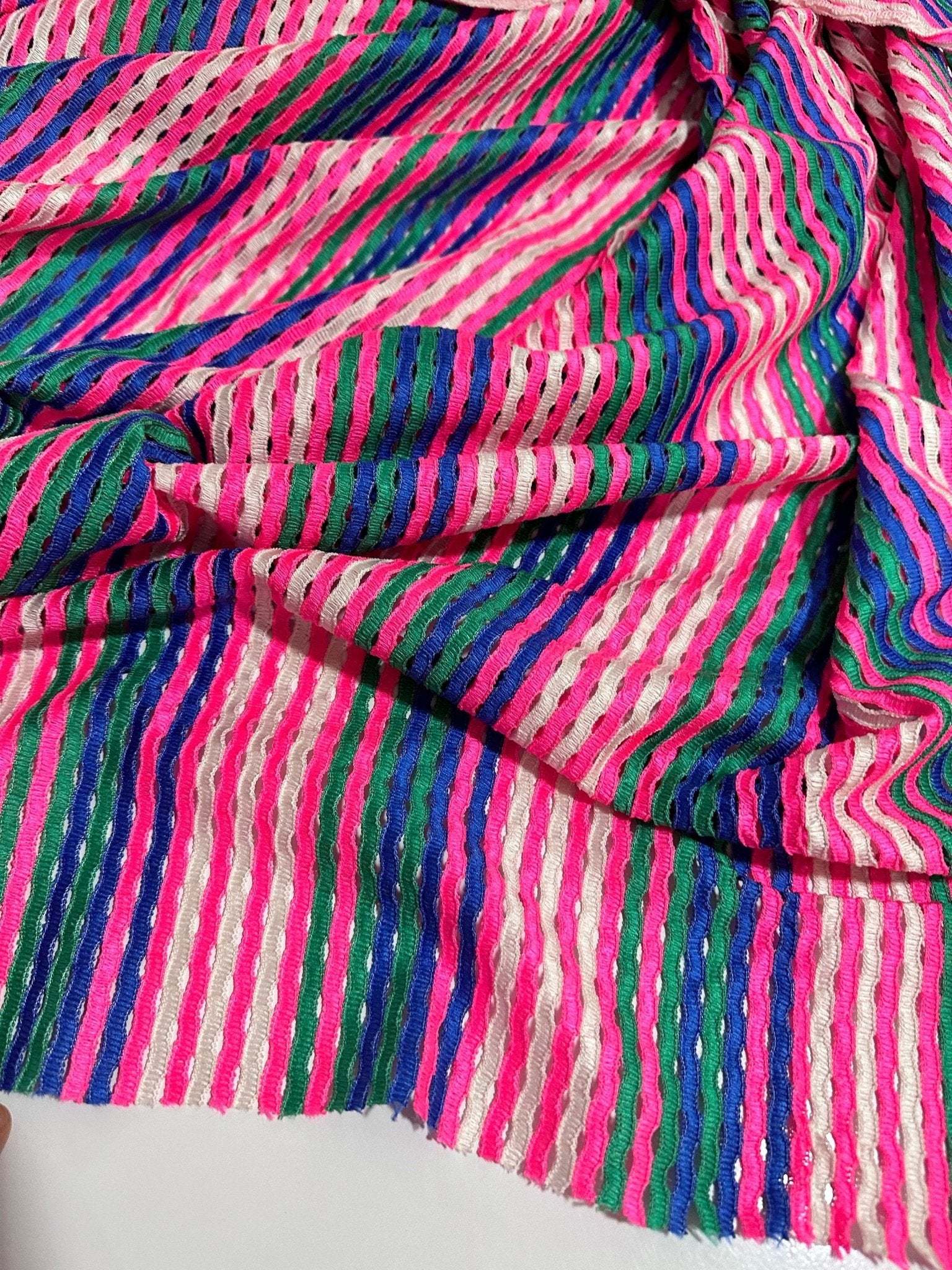 Pink striped knit jersey fabric with soft mesh texture and vibrant multicolor stripes for apparel and crafting projects