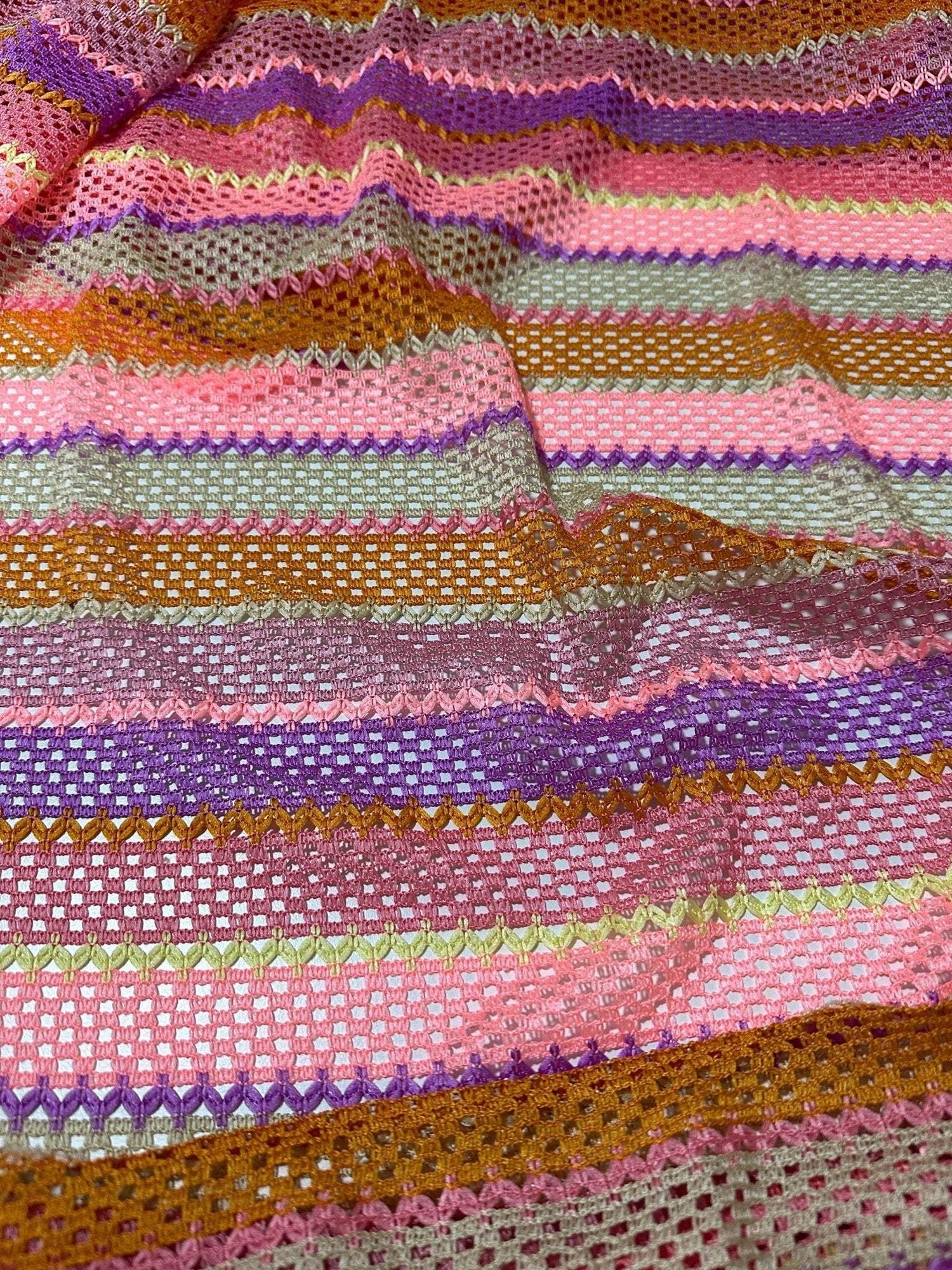 Pink striped knit jersey fabric with soft mesh texture and colorful horizontal stripes in pink, purple, orange, and green tones