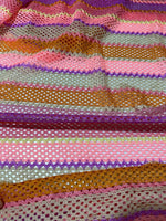 Close-up of pink striped knit jersey fabric with mesh texture and multicolor horizontal stripes for fashion and crafts