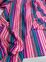 Pink striped knit jersey fabric with soft mesh texture and vibrant multicolor stripes, ideal for apparel and crafts.