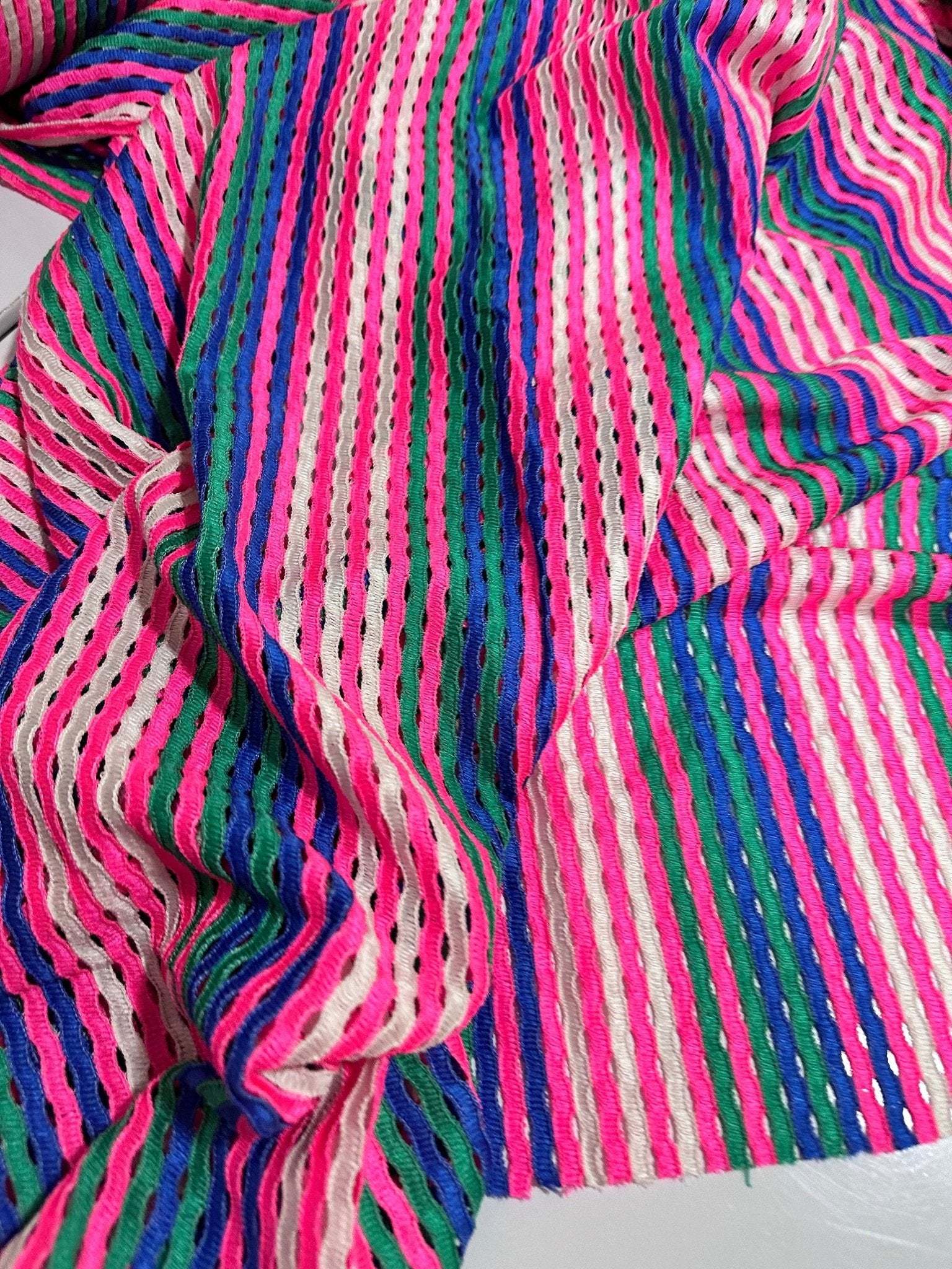 Pink striped knit jersey fabric with soft mesh texture and vibrant multicolor stripes, ideal for apparel and crafts.
