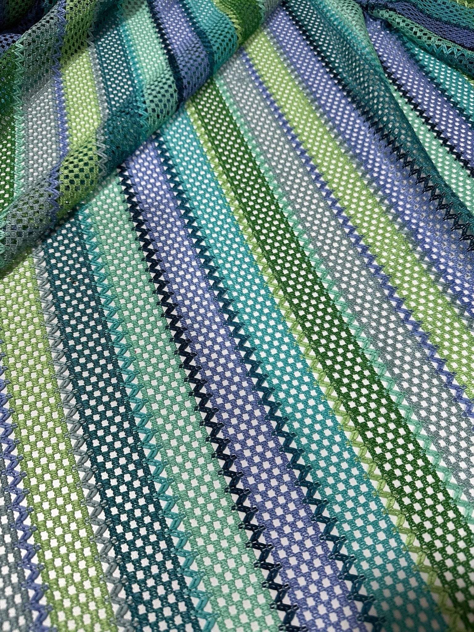 Striped knit mesh fabric with zigzag pattern in green and blue tones for creative sewing projects