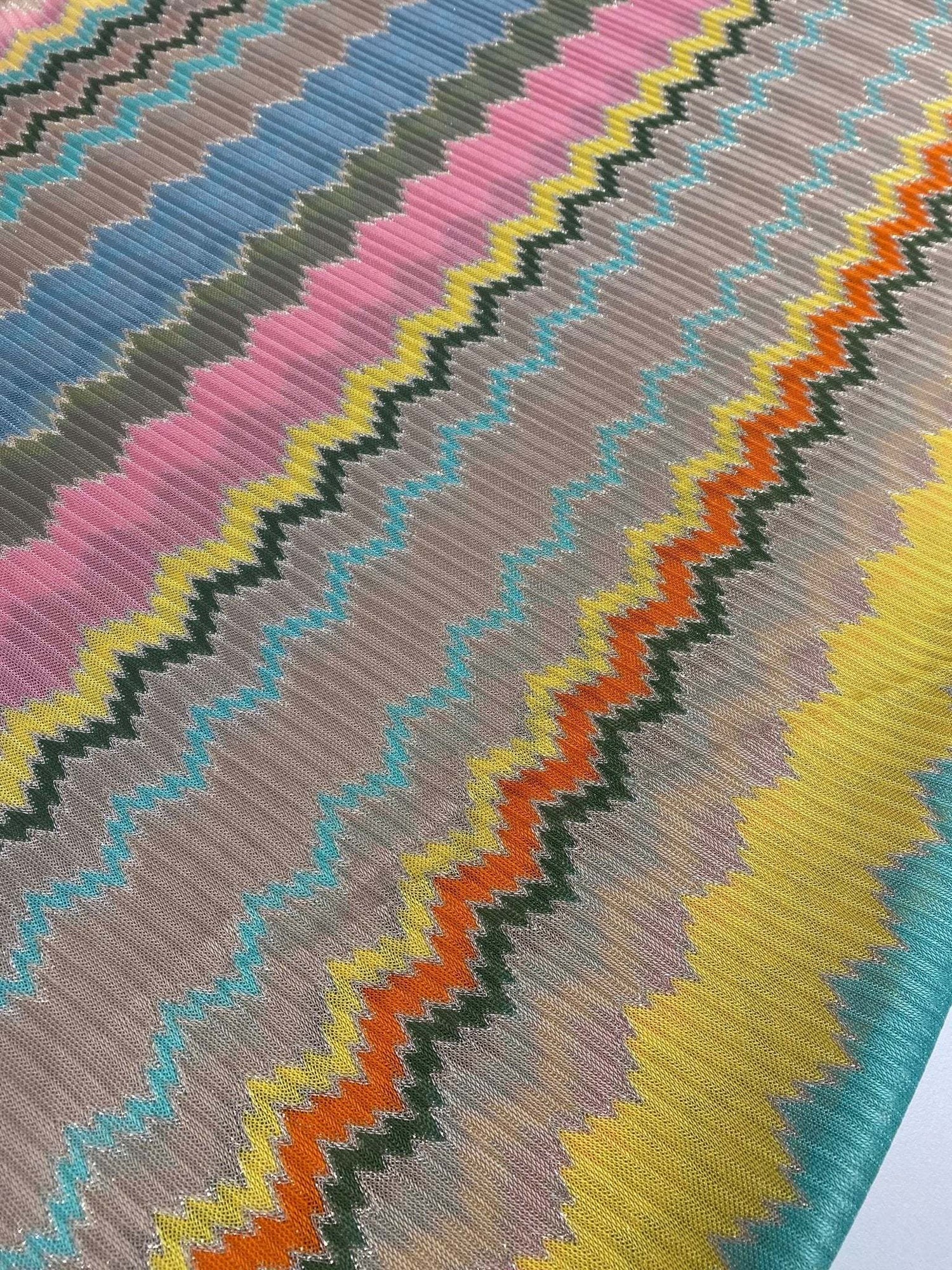 Multicolor zigzag mesh fabric with vibrant knit pattern in green, yellow, orange, pink, blue, and gray tones.