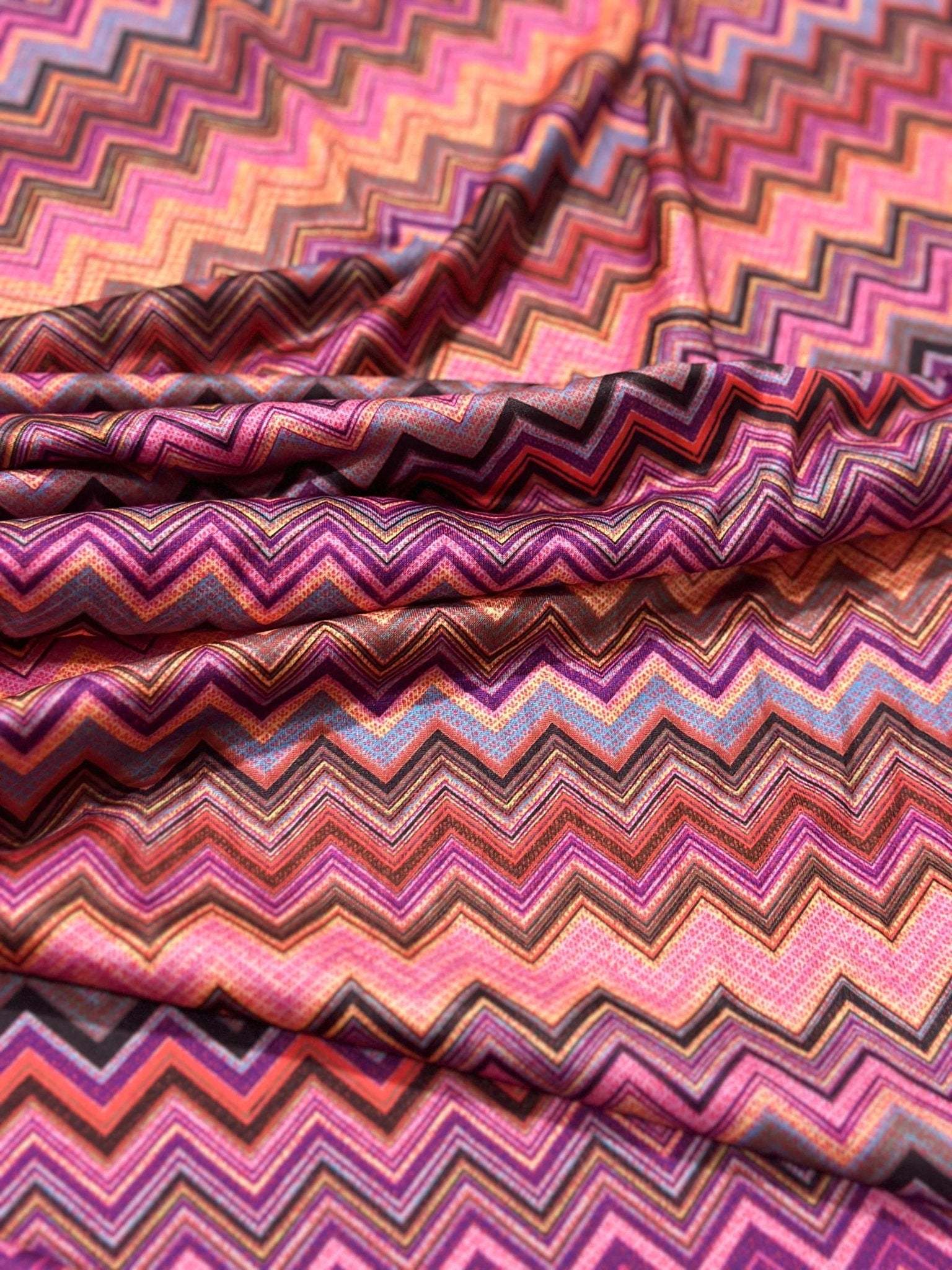 Zigzag mesh stretch fabric in vibrant pink, orange, and purple tones with 4-way stretch and stylish zigzag pattern