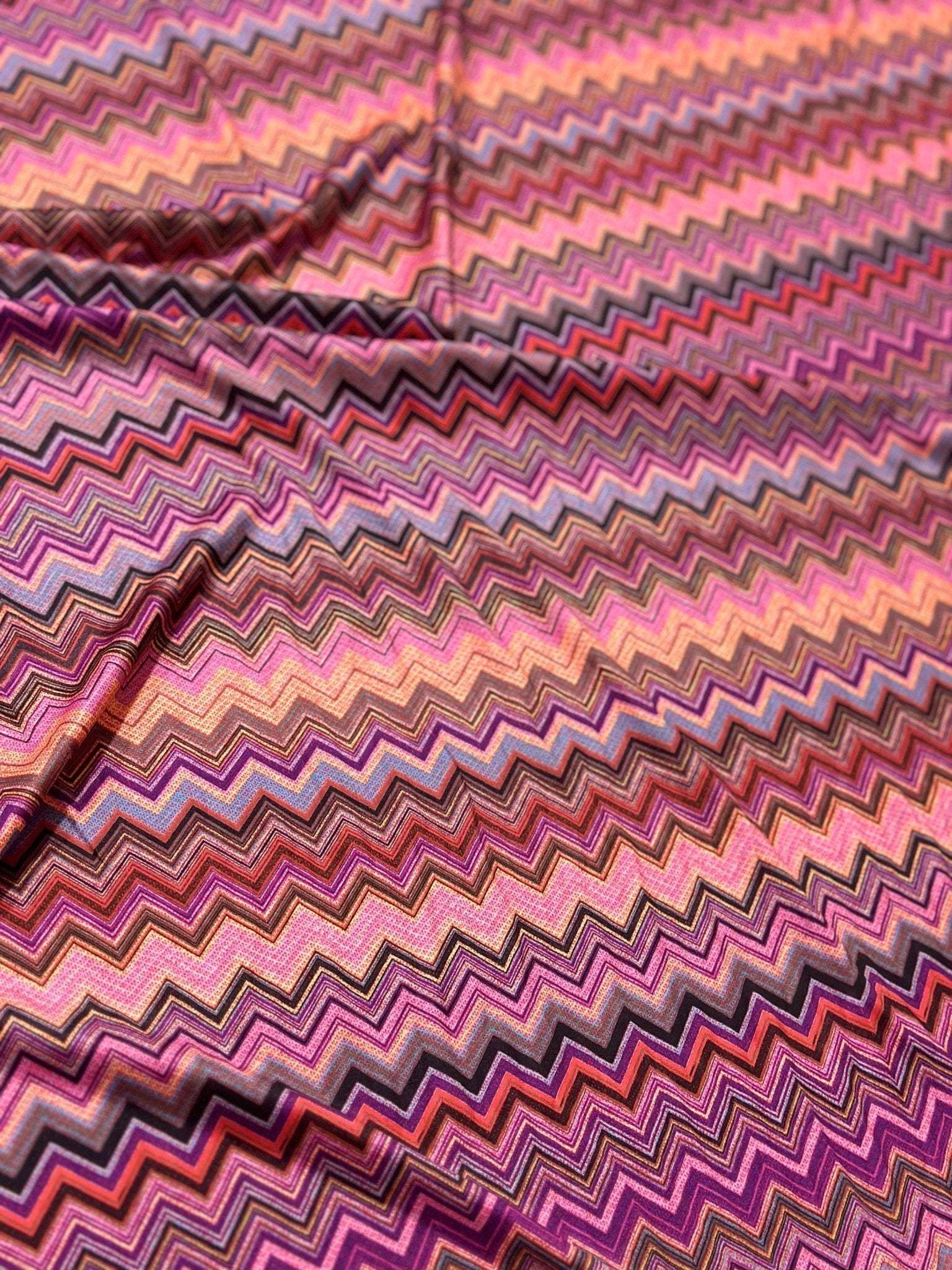 Colorful zigzag patterned mesh fabric with 4-way stretch in shades of pink, purple, and orange