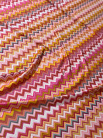 Colorful 4-way stretch fabric with zigzag pattern in shades of pink, yellow, and orange for versatile use