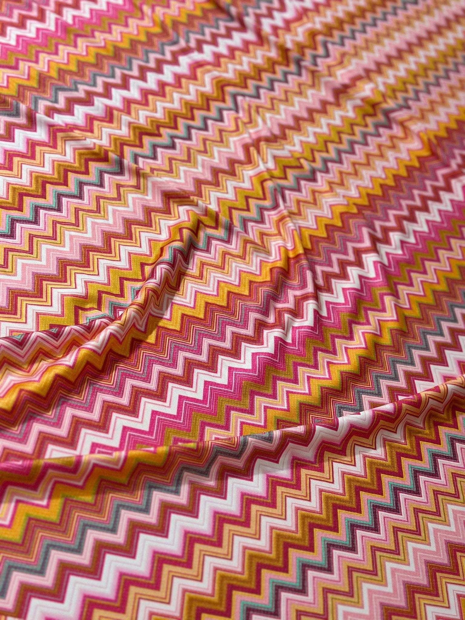 Colorful 4-way stretch fabric with zigzag pattern in shades of pink, yellow, and orange for versatile use