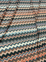 Close-up of multi-colored zigzag patterned 4-way stretch mesh fabric with blue, orange, and beige tones.