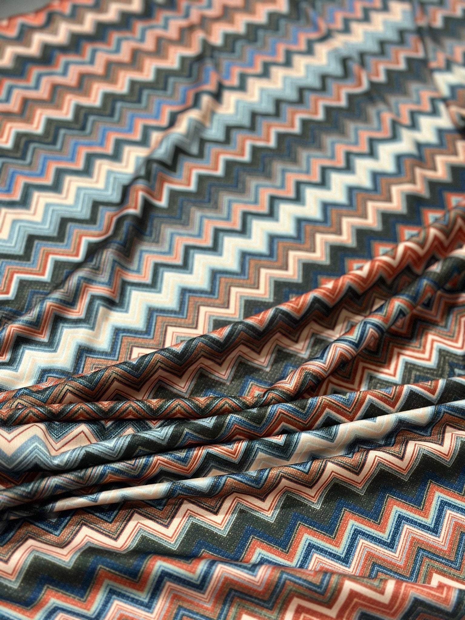 Close-up of zigzag patterned fabric in blue, brown, and beige tones with 4-way stretch mesh texture, ideal for activewear and accessories.