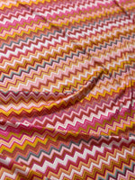 Stretch fabric with colorful zigzag pattern in red, yellow, and white tones
