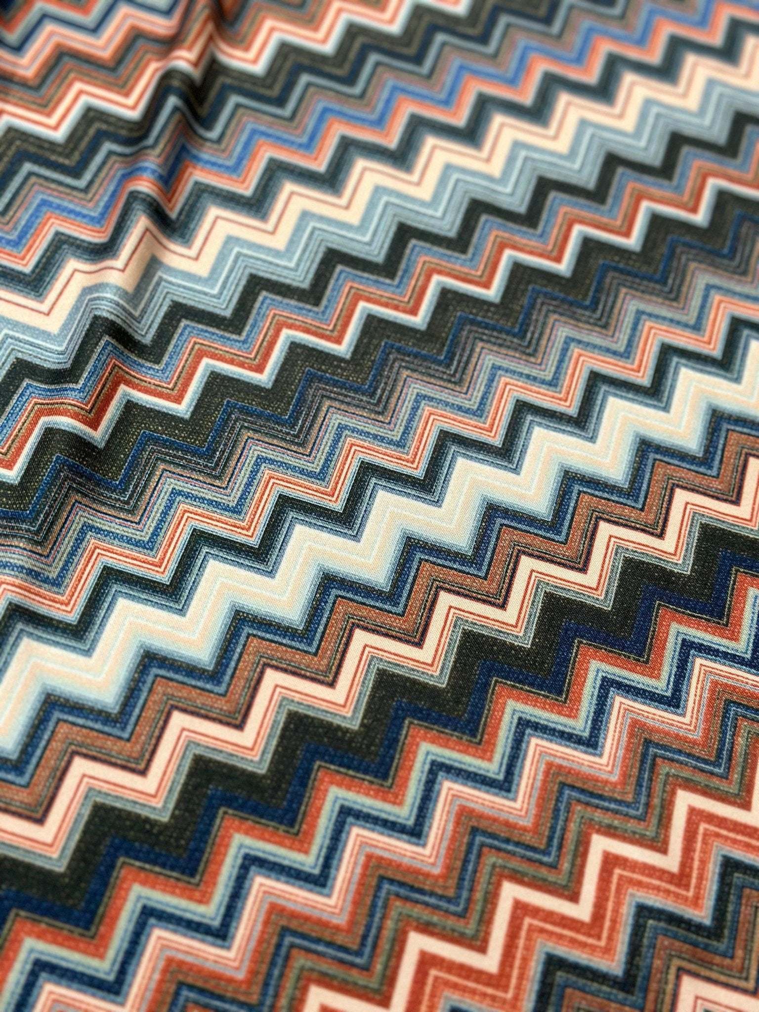 Close-up of colorful zigzag patterned fabric with 4-way stretch and breathable mesh texture for activewear and accessories