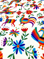 Vibrant Otomi print outdoor pillow fabric with colorful birds, deer, and floral designs on a white background for upholstery and runners.