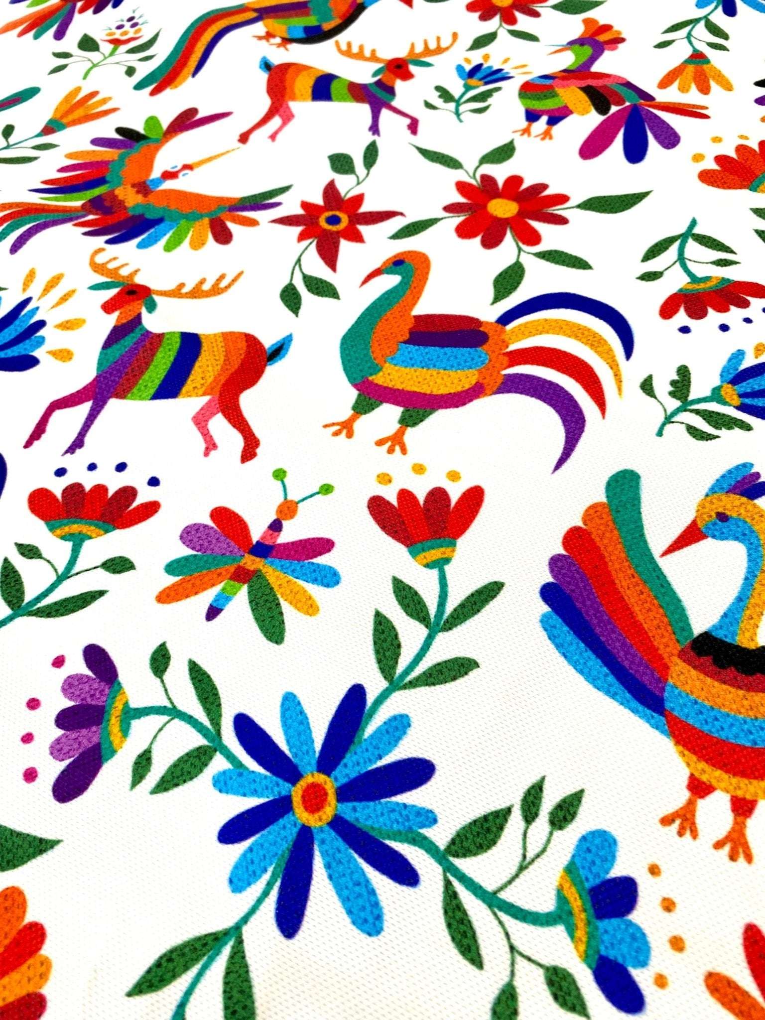 Vibrant Otomi print outdoor pillow fabric with colorful birds, deer, and floral designs on a white background for upholstery and runners.