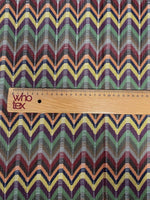 Multicolor Chevron Jacquard Fabric with zigzag pattern in green, yellow, red, and purple tones shown with wooden ruler for scale
