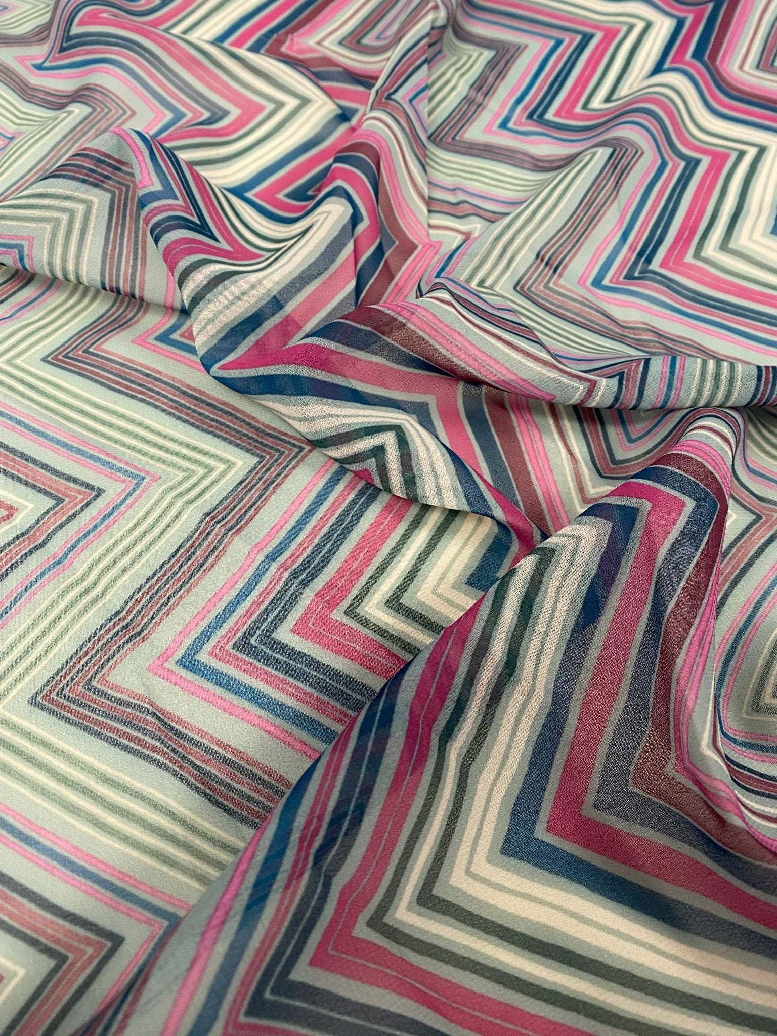 Multicolor chevron zigzag fabric with vibrant pink, blue, and gray stripes in a geometric pattern.