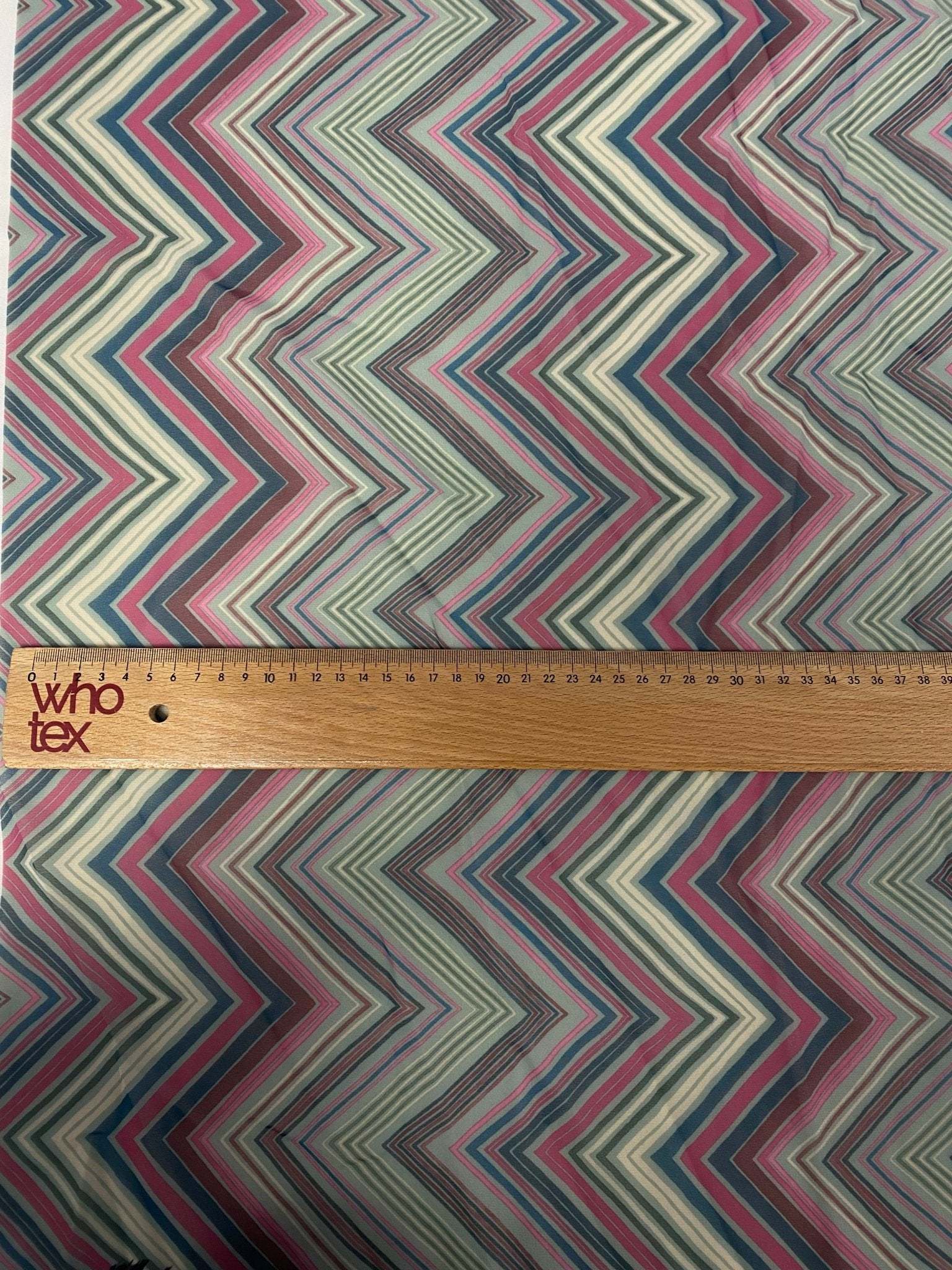 Close-up of multicolor chevron zigzag fabric with ruler showing pattern scale
