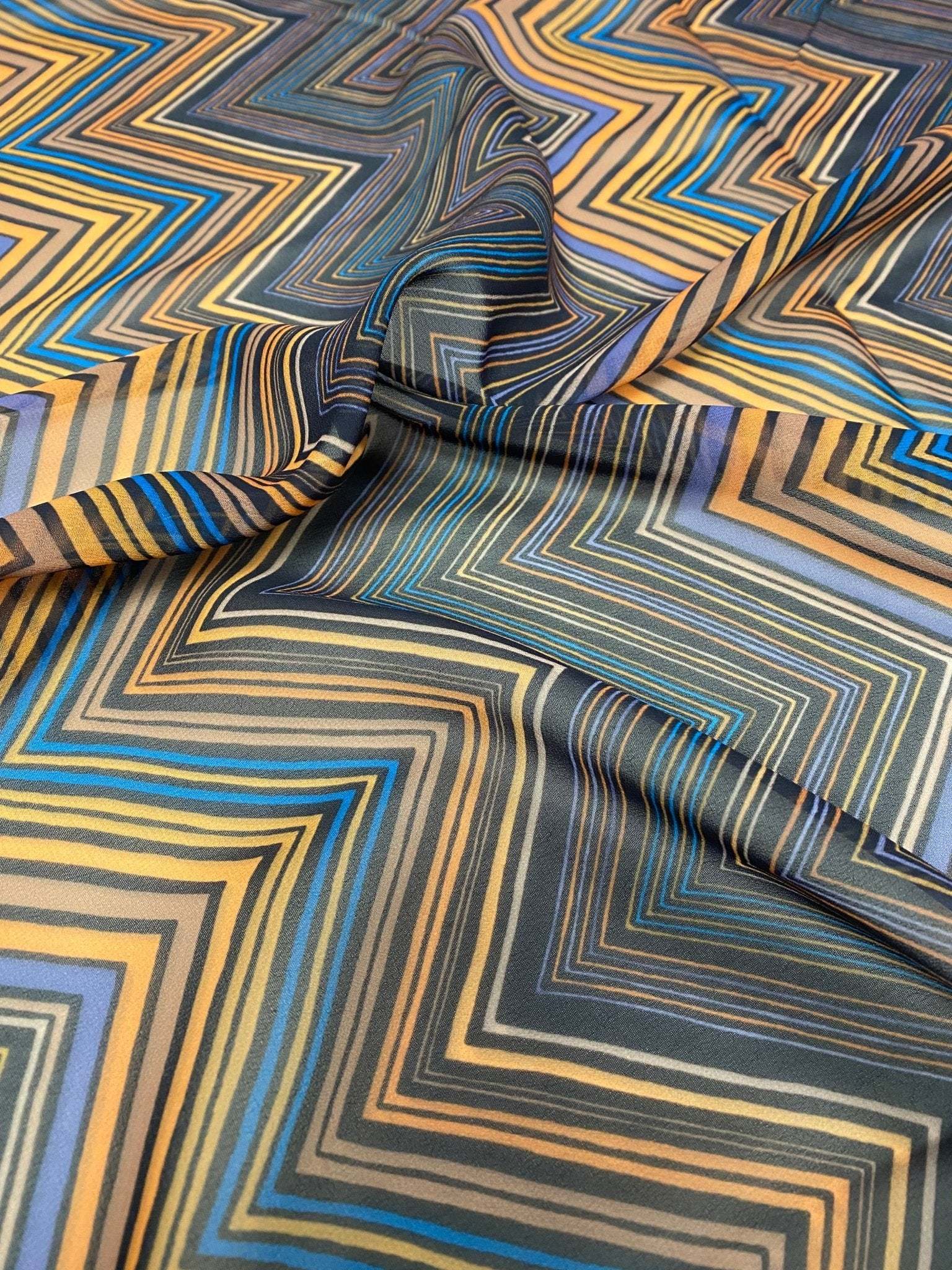 Multicolor chevron zigzag pattern fabric with blue, yellow, and black tones, ideal for sewing projects and home decor.