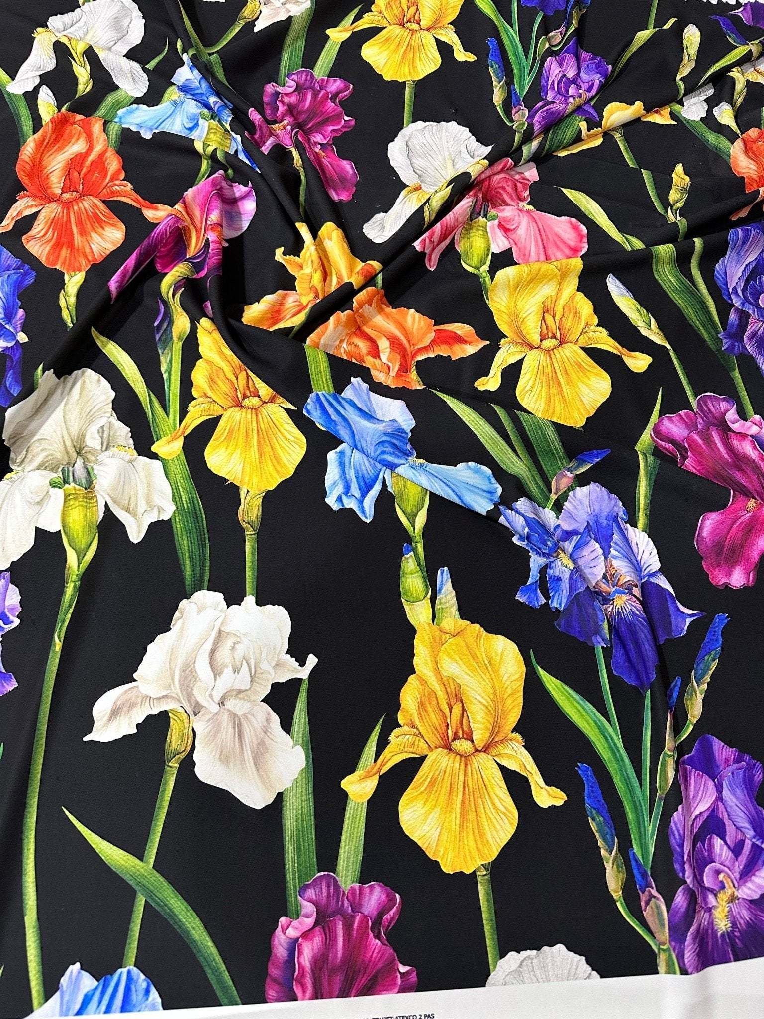 Colorful floral crepe fabric with vibrant irises on a black background, lightweight and breathable textile for sewing projects