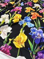 Floral crepe fabric with colorful iris flowers on black background, lightweight and breathable textile for dresses and blouses