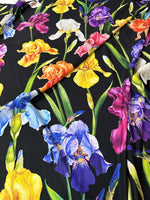 Black floral crepe fabric with colorful iris flower pattern, lightweight and soft textured material ideal for dresses and blouses