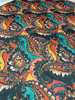 Close-up of multicolor paisley print fabric with vibrant orange, teal, and black patterns