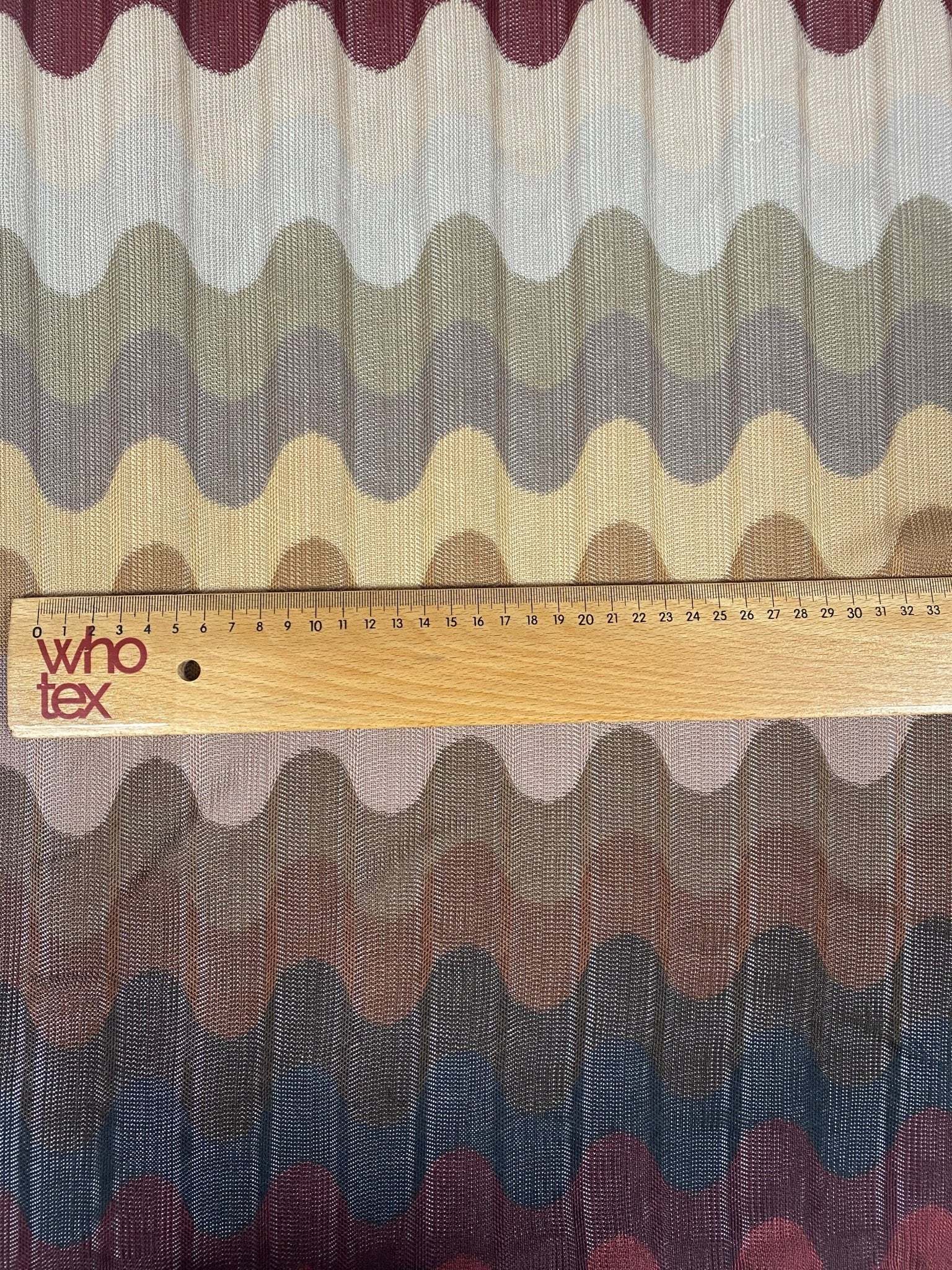 Multicolor pleated wave fabric with zigzag knit pattern in earthy tones and ruler for scale