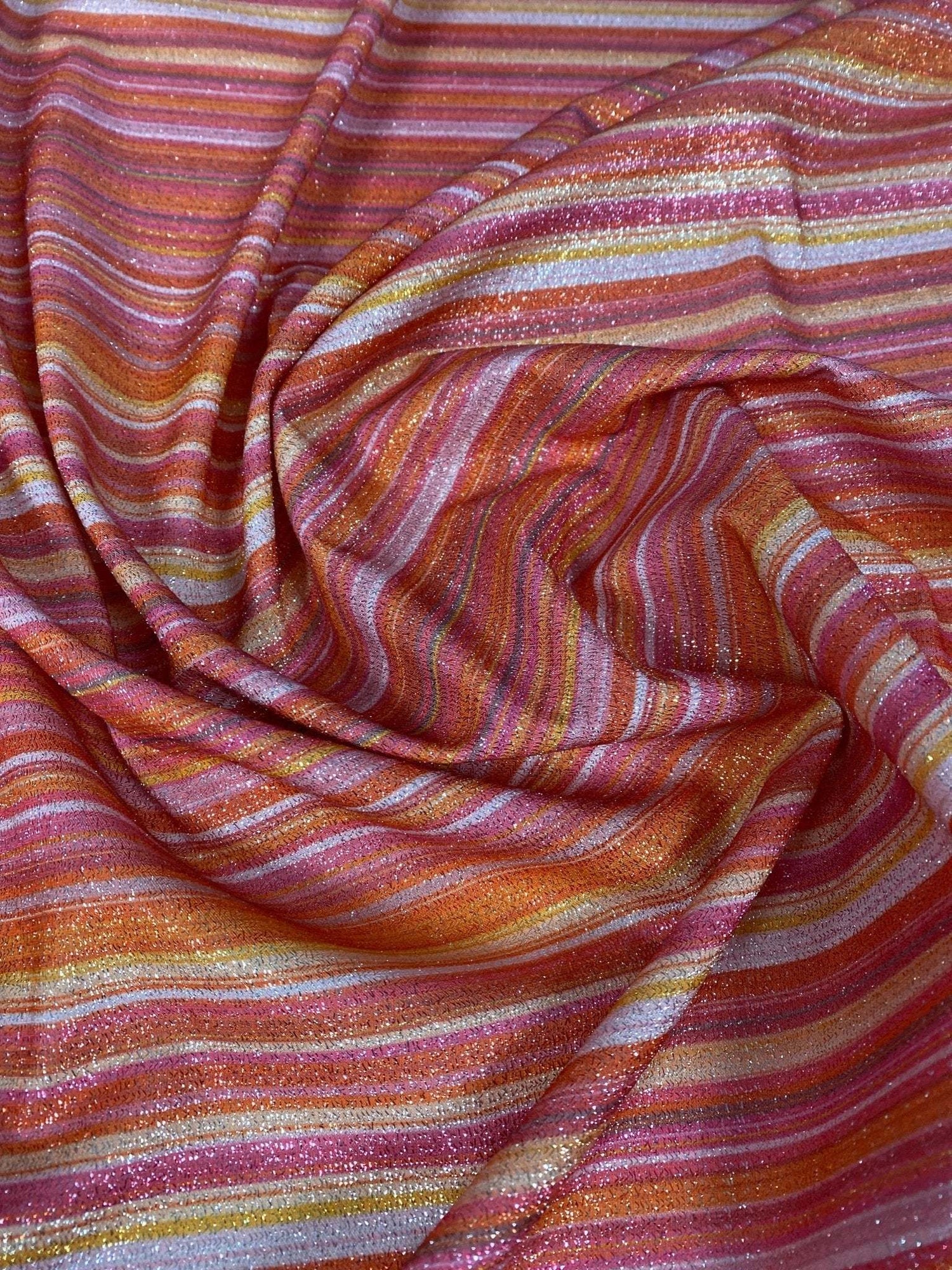Multicolor striped glitter fabric in red, orange, and pink tones with gold lurex shimmer and 4-way stretch polyester blend