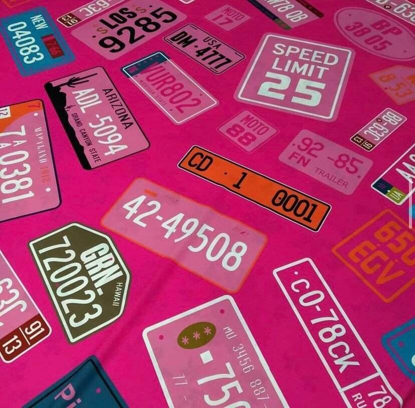 Pink fabric with colorful number plate and speed limit sign patterns for crafting and sewing projects