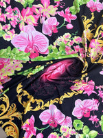 Orchid floral swirl print fabric with vibrant pink orchids and green leaves on a black background with gold ornamental accents