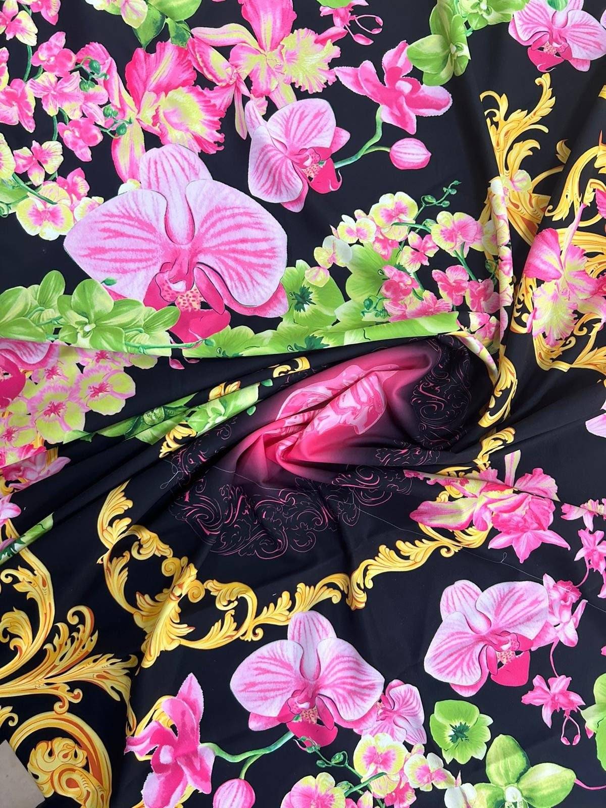 Orchid floral swirl print fabric with vibrant pink orchids and green leaves on a black background with gold ornamental accents
