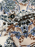 Close-up of blue, brown, and beige ornamental ethnic print fabric with intricate pattern and 150cm width