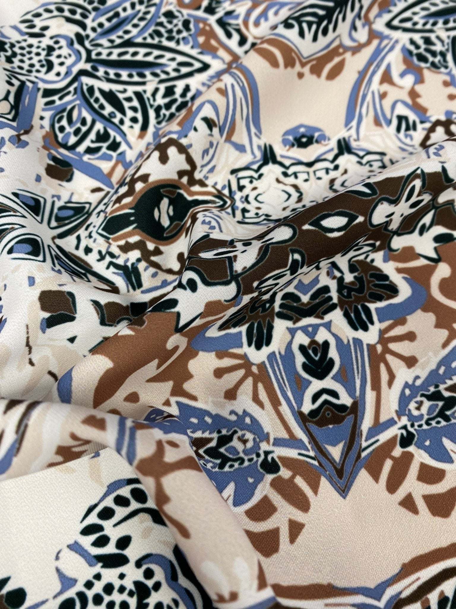 Close-up of blue, brown, and beige ornamental ethnic print fabric with intricate pattern and 150cm width