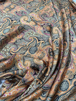 Close-up of black and orange paisley fabric with intricate swirling patterns and floral details