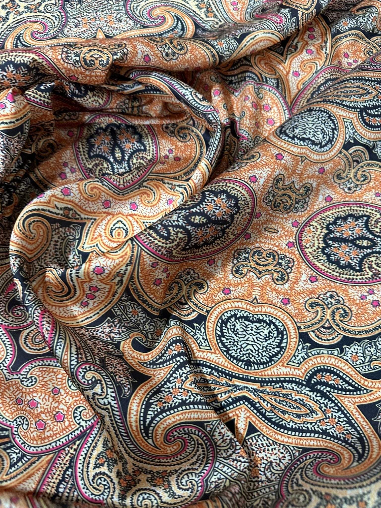 Black and orange paisley patterned fabric with intricate decorative design and 150cm width