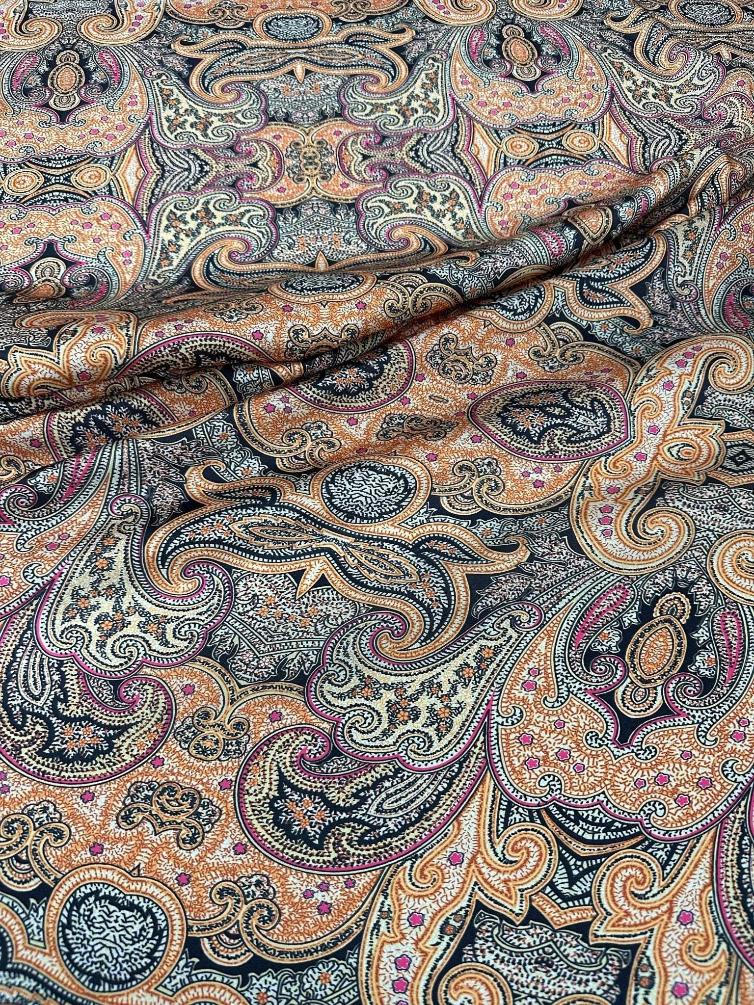 Black and orange paisley patterned fabric with intricate decorative design and 150cm width