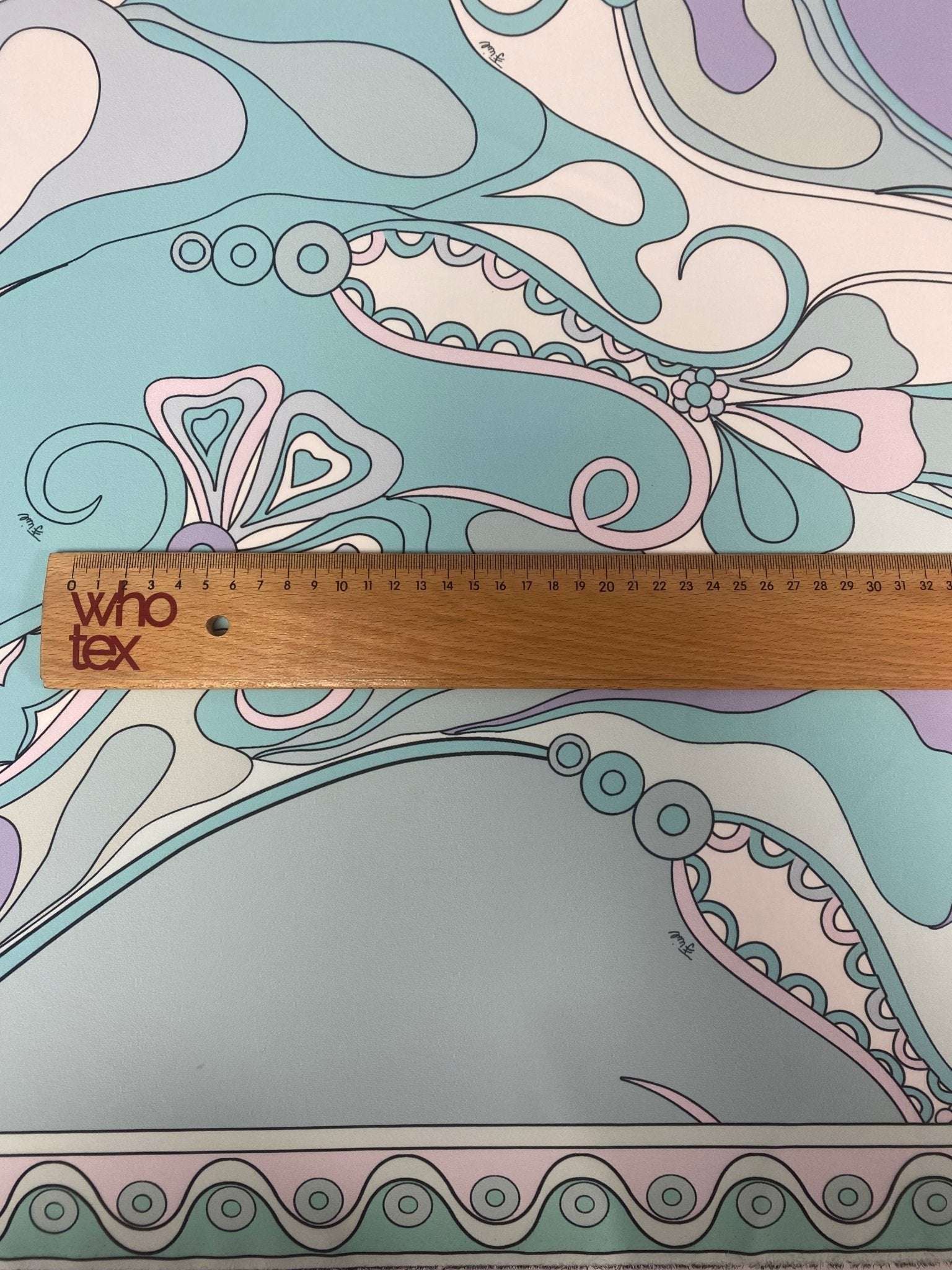 Pastel abstract swirl fabric with soft pastel colors and intricate swirl patterns shown with ruler for scale