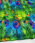 Vibrant green peacock feather fabric with detailed colorful eye patterns, sold by the yard for sewing and crafting projects