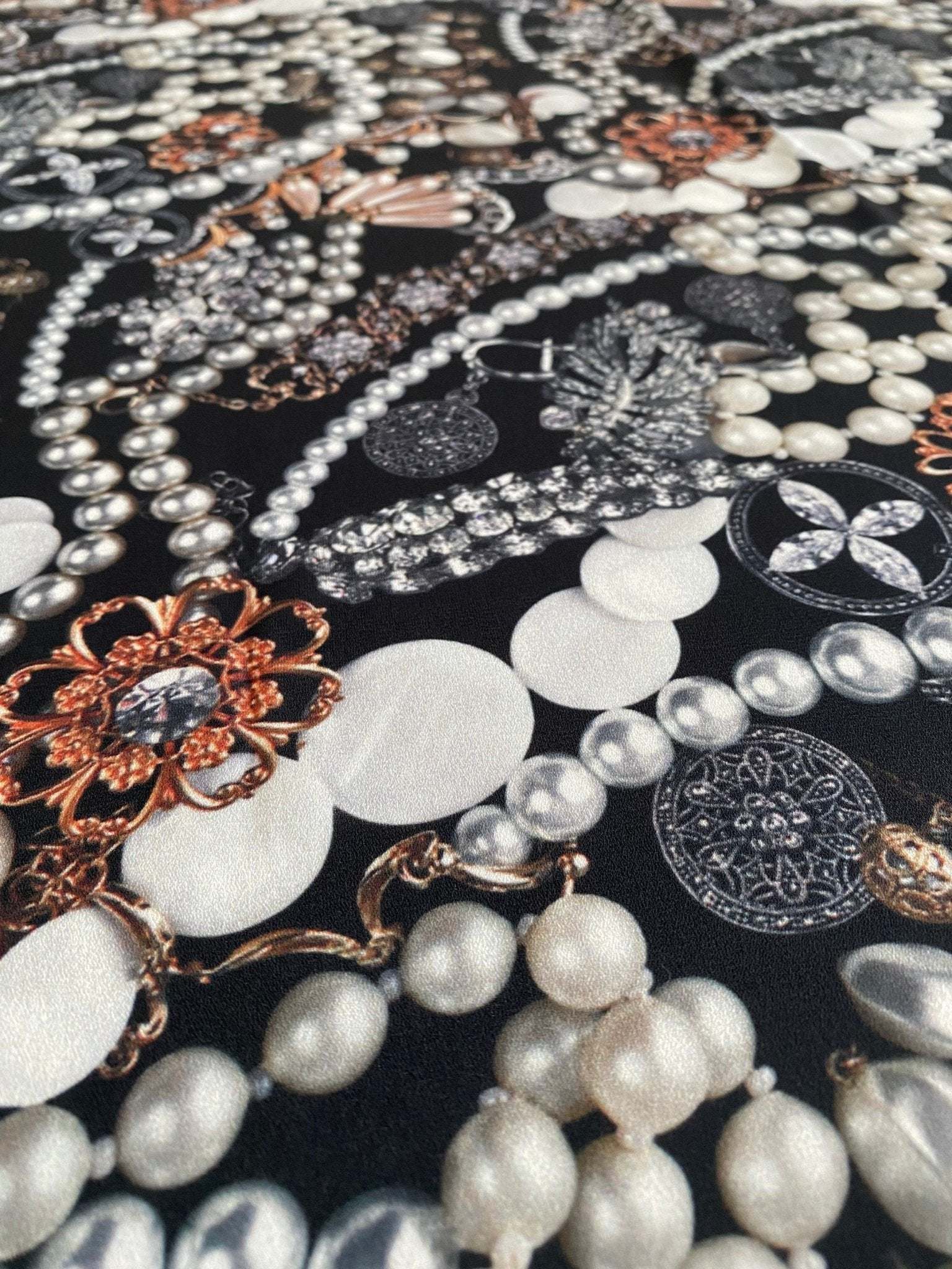 Close-up of black jewelry fabric with intricate pearl and gemstone pattern for elegant accessories