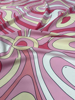 Close-up of pink and yellow psychedelic swirl print fabric with vibrant swirled patterns and smooth texture