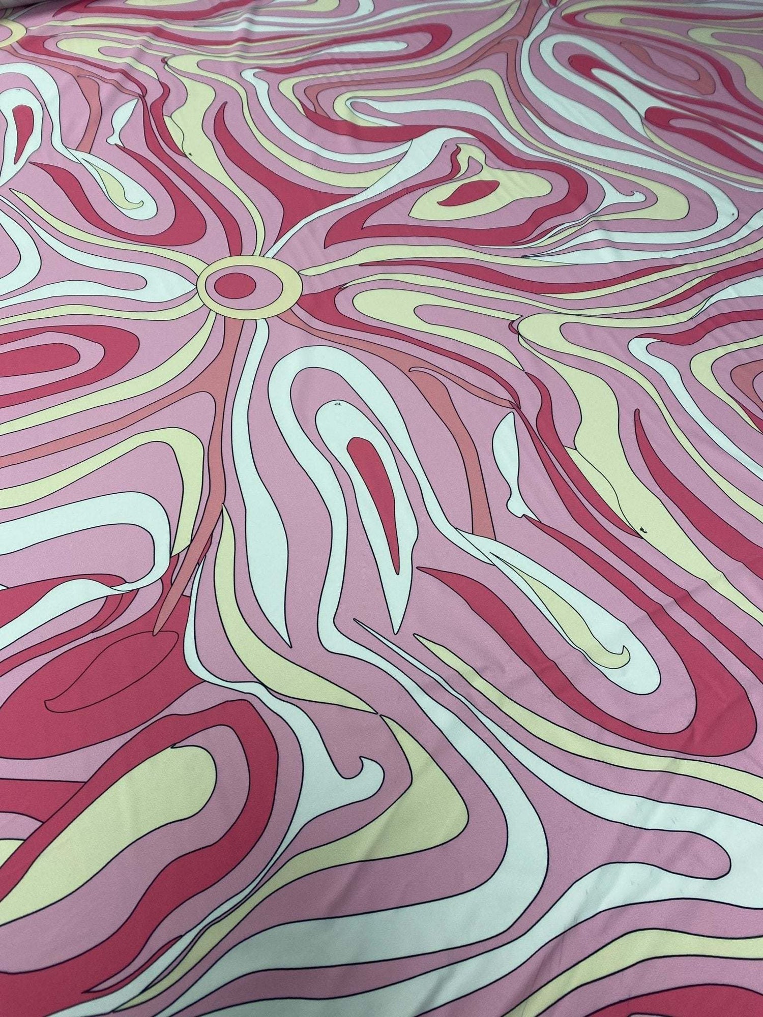 Pink and yellow psychedelic swirl print fabric with vibrant abstract design and smooth texture