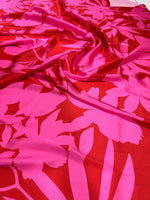 Tropical pink and red fabric with vibrant floral pattern, ideal for sewing projects and home decor.