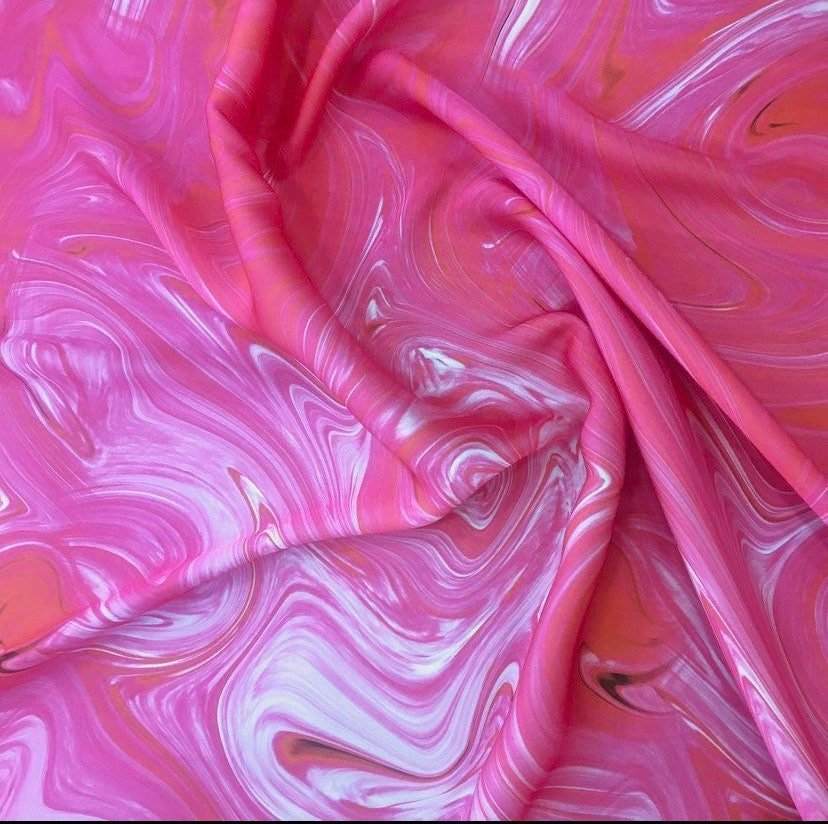 Close-up of vibrant pink tie dye fabric with swirling patterns, ideal for crafts and sewing projects